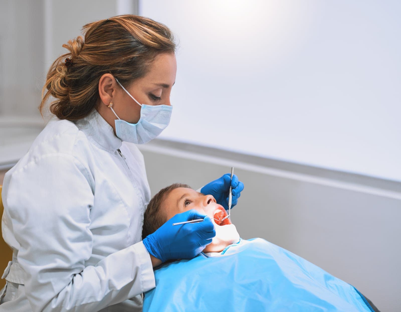 A dentist carefully checking a young patient at Manor House Dental Practice